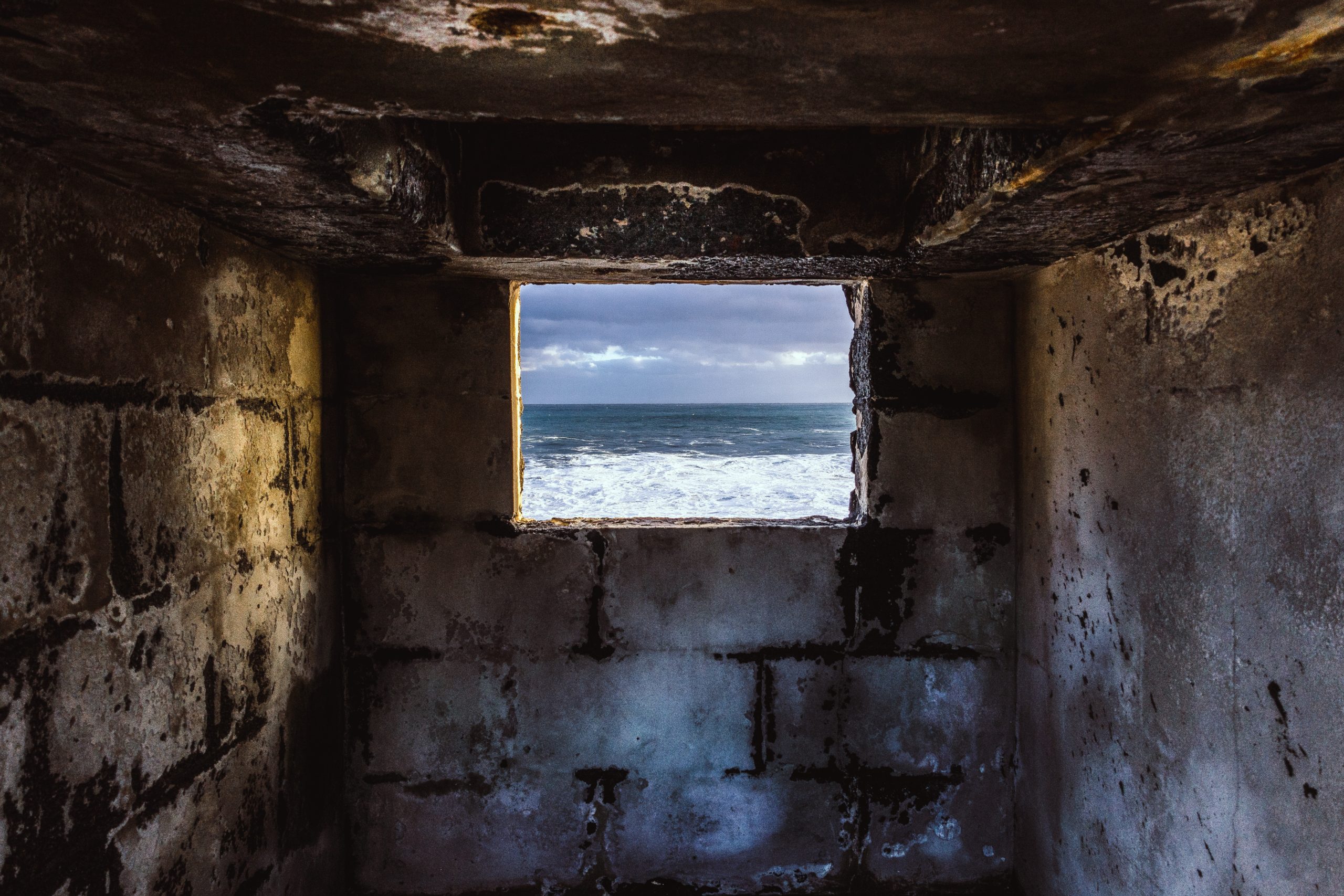 dank and desolate cinder block cell with window open to beach