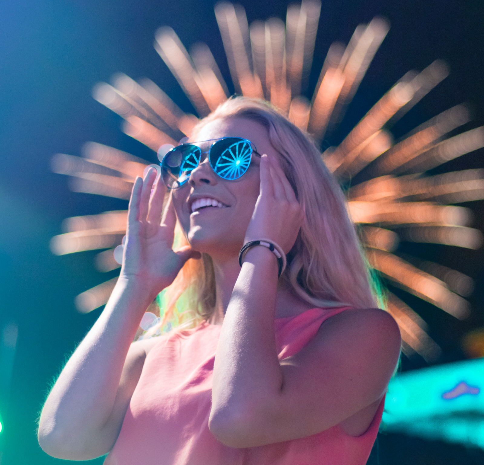 Excited woman with dark sunglasses and fireworks in background